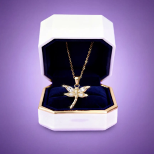 Gold dragonfly necklace presented in a luxury jewelry gift box on lilac background.