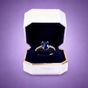 Gold ring with deep sapphire gemstone displayed inside a luxury jewelry presentation box.